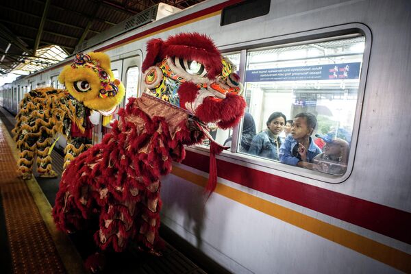 Пассажиры смотрят на выступление артистов, исполняющих Танец льва, на железнодорожной станции Гамбир во время празднования Нового года по лунному календарю в Джакарте
