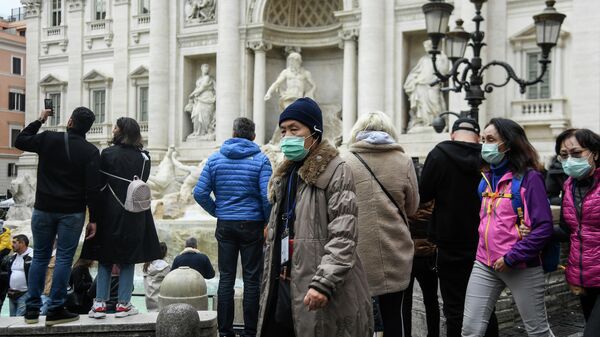 Туристы в респираторных масках возле фонтана Треви в центре Рима 