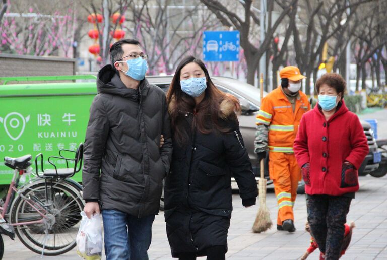 Прохожие в медицинских масках на улице Пекина, КНР Прохожие в медицинских масках на улице Пекина, КНР
