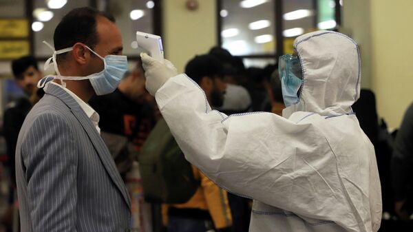 Медицинский работник проводит осмотр пассажира в аэропорту Басры, Ирак