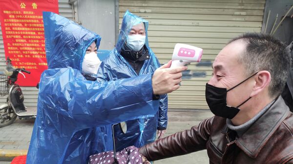 Измерение температуры тела мужчины на улице в городе Ухань, провинция Хубэй