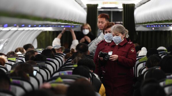 Сотрудники санитарно-карантинного пункта обследуют при помощи тепловизора пассажиров рейса авиакомпании S7 в аэропорту Толмачево