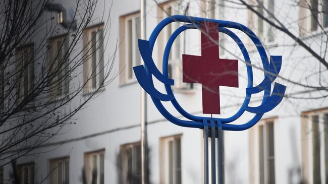 Знак красного креста на здании больницы. Архивное фото