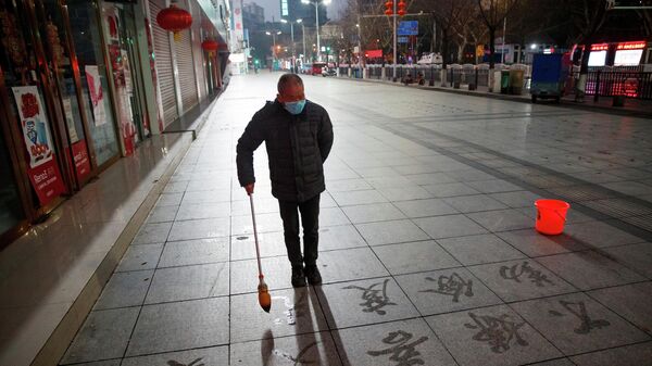 Мужчина рисует иероглифы на тротуаре в китайском городе Цзюцзян