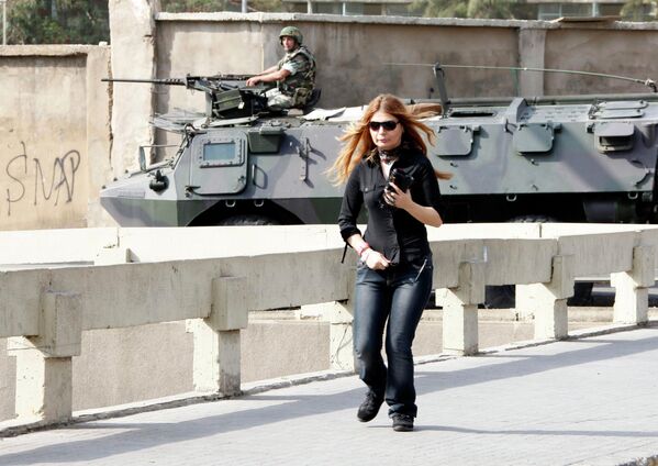 Женщина бежит в укрытие во время столкновений между противниками и сторонниками правительства в Бейруте