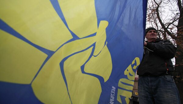 Мужчина разворачивает флаг националистической партии Свобода возле агитационной палатки во Львове, архивное фото