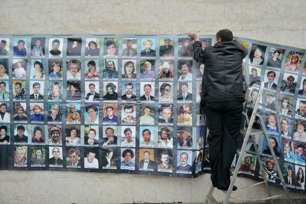 Мужчина вешает фотографии в день памяти по погибшим в результате теракта на Дубровке