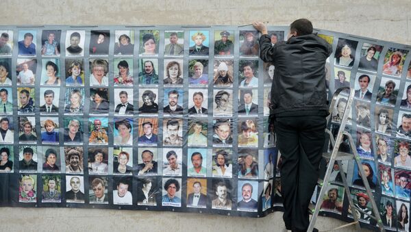 Мужчина вешает фотографии в день памяти по погибшим в результате теракта на Дубровке