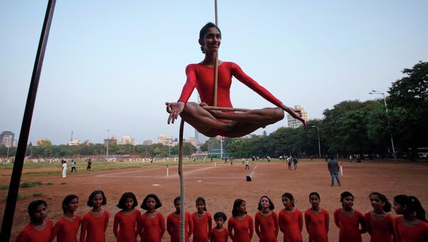 Девушка демонстрирует индийскую гимнастику Mallakhamb