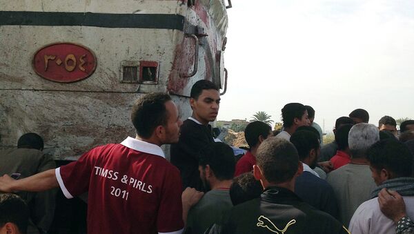 Люди на месте столкновения поезда и автобуса в Каире, Египет