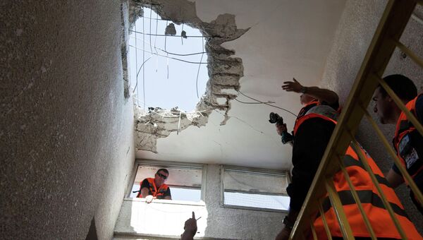 Израильские спасатели осматривают крышу здания в Ашкелоне, пострадавшем от ракетного удара