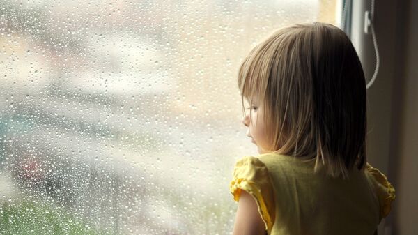 Девочка стоит у окна. Архивное фото