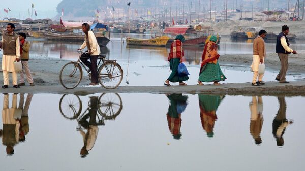 Люди идут по берегу реки Ганг накануне празника «Кумбха Мела»