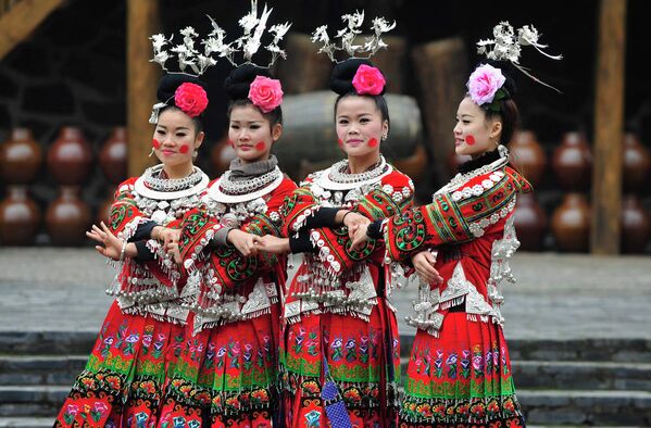 Женщины народности мяо в провинции Гуйчжоу танцуют в традиционных платьях за день до празднования Нового года, Китай