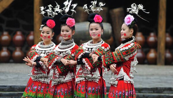 Женщины народности мяо в провинции Гуйчжоу танцуют в традиционных платьях за день до празднования Нового года, Китай