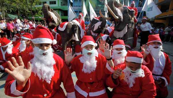 Дети и слоны в костюмах Санта-Клауса во время празднования Рождества в тайской провинции Аюттхая