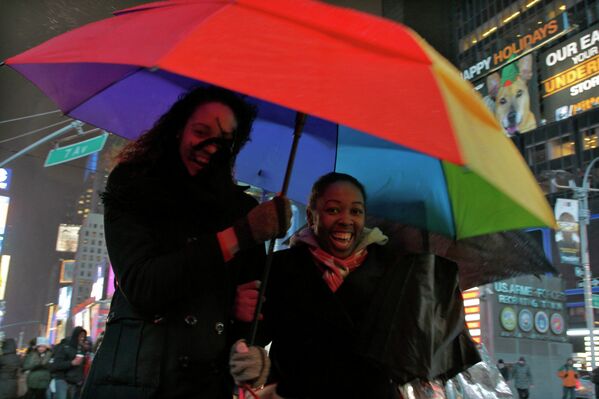 Женщины укрываются от дождя на Таймс-сквер в Нью-Йорке