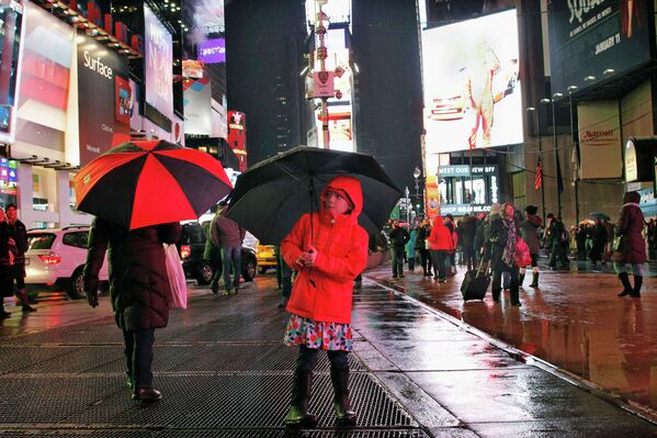 Девочка укрывается от дождя на Таймс-сквер в Нью-Йорке