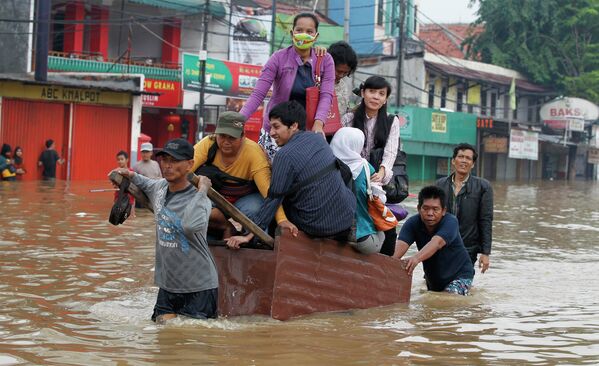Жители Джакарты передвигаются по затопленной улице