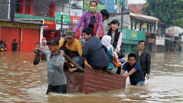 Жители Джакарты передвигаются по затопленной улице