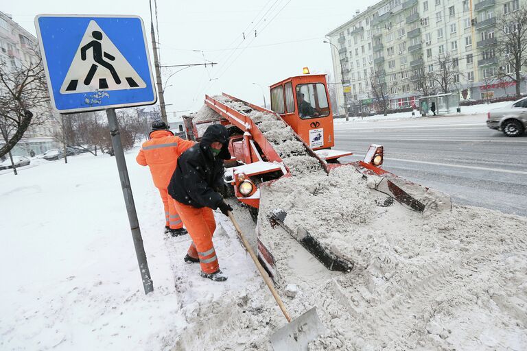 Сотрудники коммунальных служб убирают снег на одной из улиц Москвы