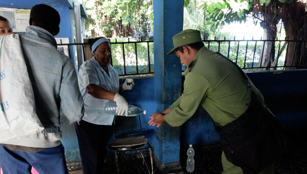 Люди моют руки дезинфицирующим средством у входа в автовокзал в Гаване, Куба