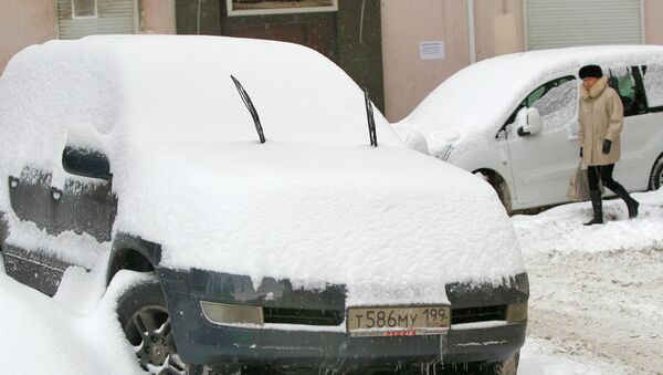 Снег на припаркованных автомобилях в Москве