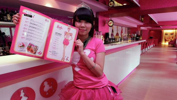 Официантка демонстрирует меню кафе в стиле куклы Барби в Тайпее, Тайвань