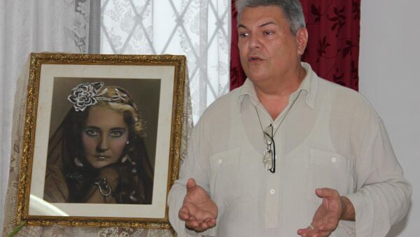 Организатор конкурса пения имени Марьяны де Гонич в Гаване Уго Осле рядом с портретом русской певицы