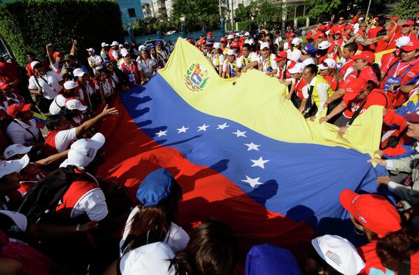 Венесуэльские студенты держат свой национальный флаг в знак поддержки президента Уго Чавеса в Гаване