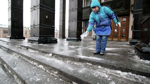 Женщина посыпает реагентом ступеньки у здания Государственной библиотеки имени Ленина в центре Мосвкы
