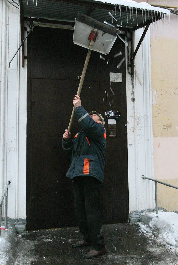 Мужчина чистит козырек подъезда от сосулек в Москве