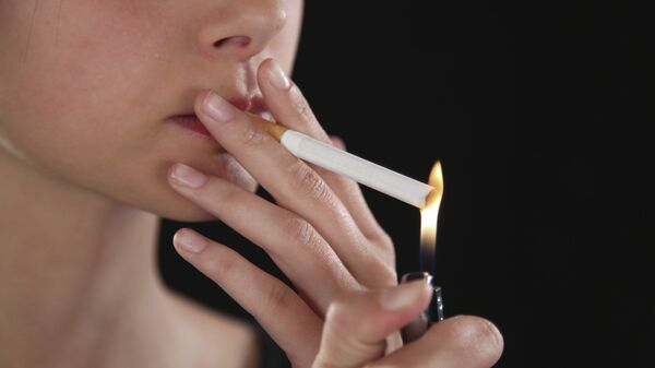 Женщина поджигает сигарету