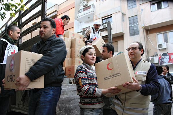 Добровольцы Сирийского Арабского Красного Полумесяца и местные жители разгружают продовольственную помощь.