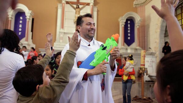 Католический священник Умберто Альварес в костюме с изображениями супергероев во время службы