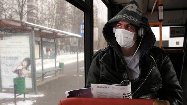 Молодой человек в защитной маске в автобусе. Архив