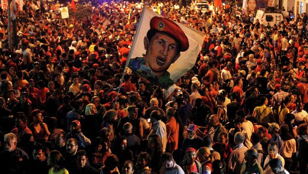 Венесуэльцы держат в руках флаг с изображением умершего от рака Уго Чавеса