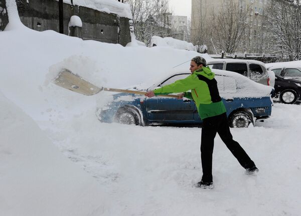 Житель Мурманска очищает от снега проезд для автомобиля после сильного снегопада