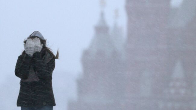 Девушка закрывает лицо от снега во время метели. Архивное фото