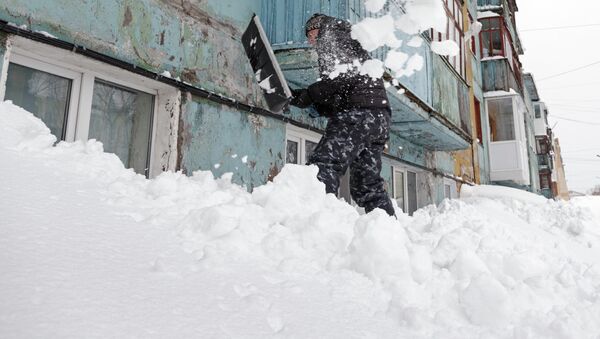 Жильцы очищают от снега окна первых этажей домов после сильного снегопада в Петропавловске-Камчатском