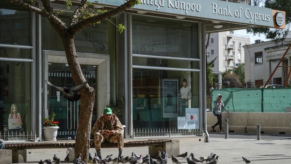 Мужчина кормит голубей у закрытого офиса Bank of Cyprus в Никосии