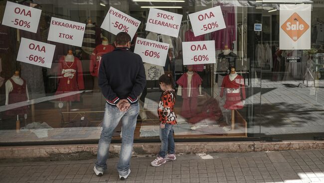 Люди смотрят на объявления о скидках в магазине города Никосии