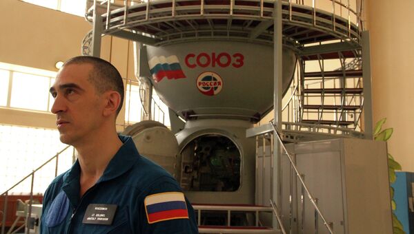 Космонавт Анатолий Иванишин на фоне тренажера корабля