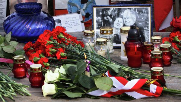 Поминальные свечи, цветы и фотографии жертв у памятного камня, установленного на месте крушения польского самолета Ту-154