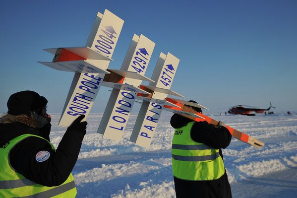 Сотрудники дрейфующей ледовой базы Барнео, находящейся в Арктике, несут символический указательный столб