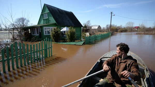 Мужчина плывет на лодке по подтопленной улице в деревне Русско в Новгородской области.