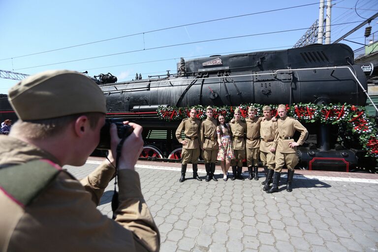 Молодые люди в военной форме времен Великой Отечественной войны стоят у ретро-поезда Победа