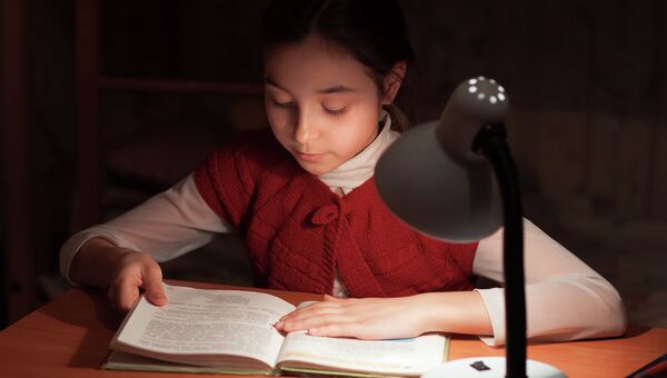 Девочка читает при свете лампы. Архивное фото