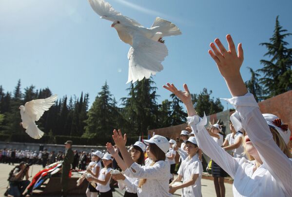 Школьники выпускают голубей на церемонии возложения цветов к Мемориалу