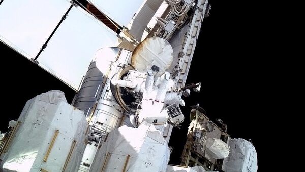 Астронавты Крис Кэссиди и Том Машберн заходят в люк шлюзового модуля Quest после выхода в открытый космос для ликвидации утечки аммиака